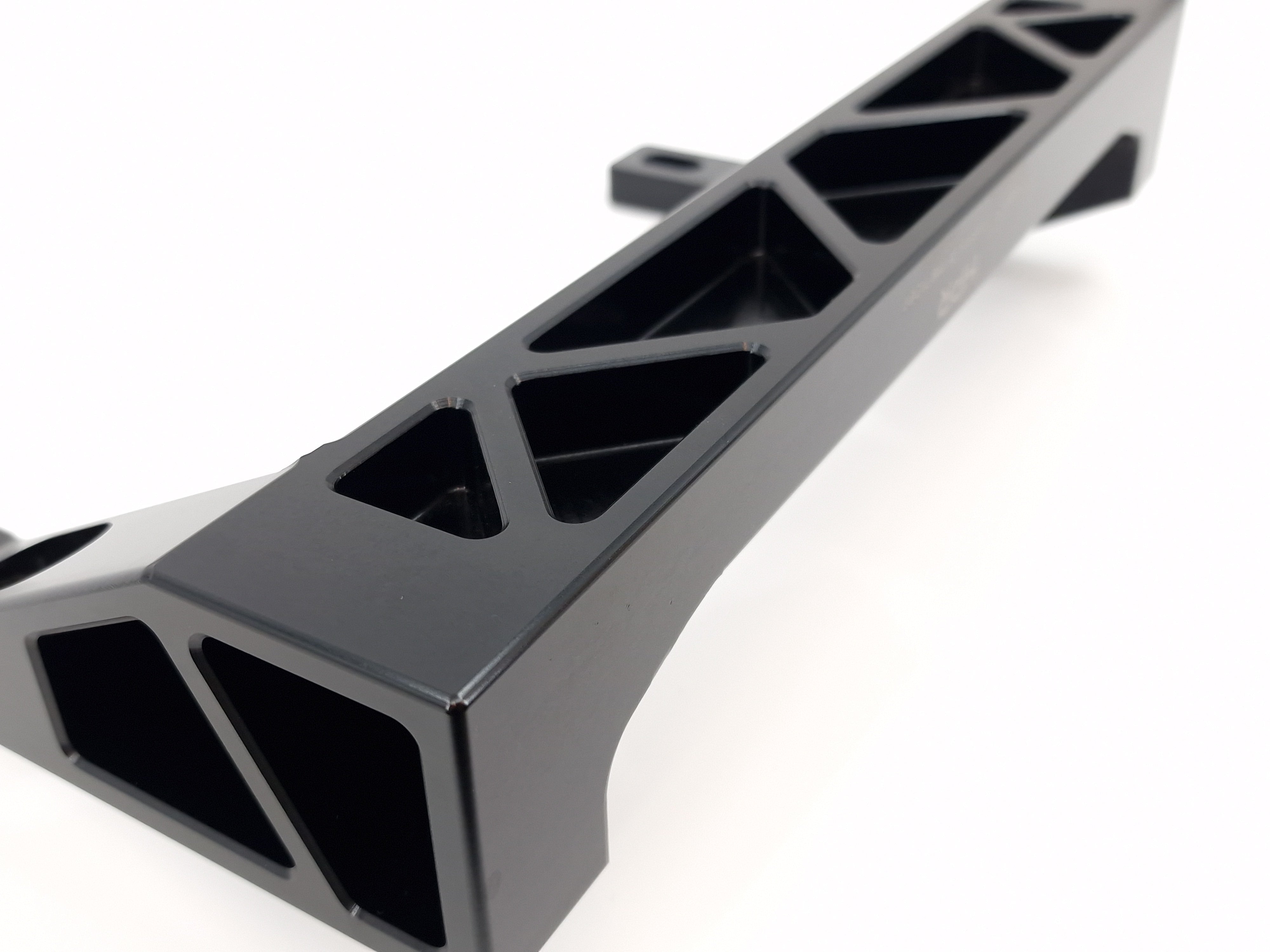 Metal chassis crossmember with black and silver diagonal cutout sections
