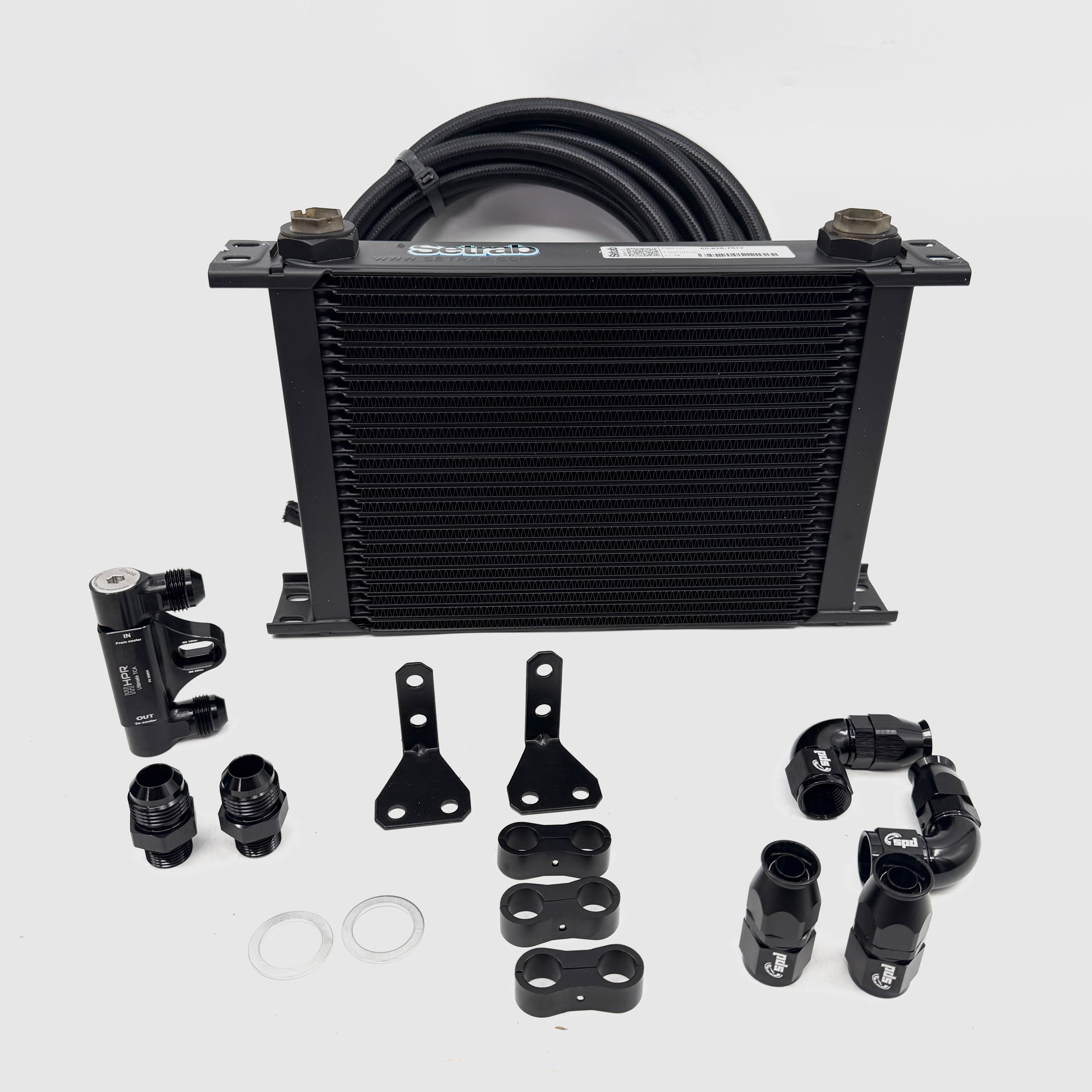 Oil cooler kit showing black heat exchanger, hoses, adapter blocks, and hardware